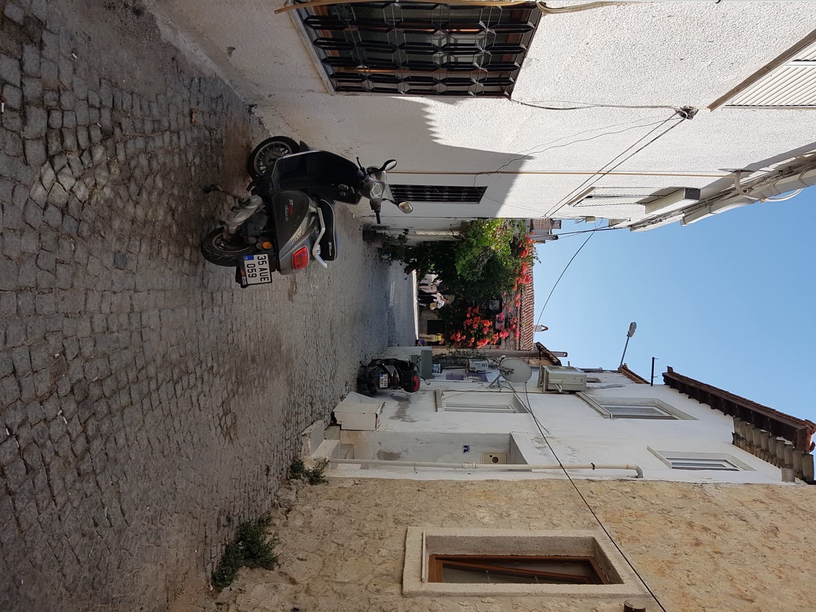 Cobbled lane between whitewashed and bare stone houses in Alacati old town