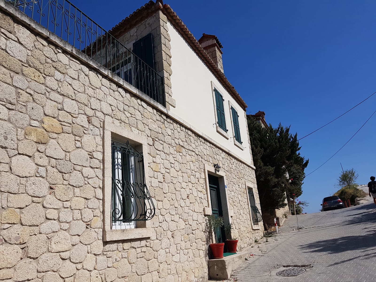 Two-story Alacati stone house with load-bearing masonry walls and green timber shutters