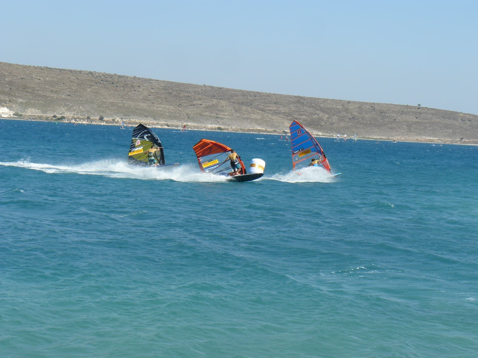 Windsurfers racing at speed on flat water during the Windsurf World Cup in Alacati bay